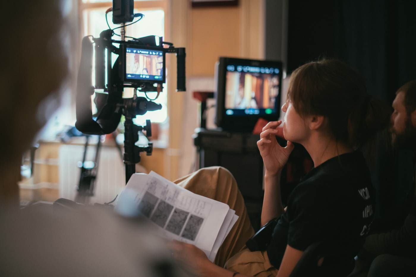 A crew member watching the monitor with a script